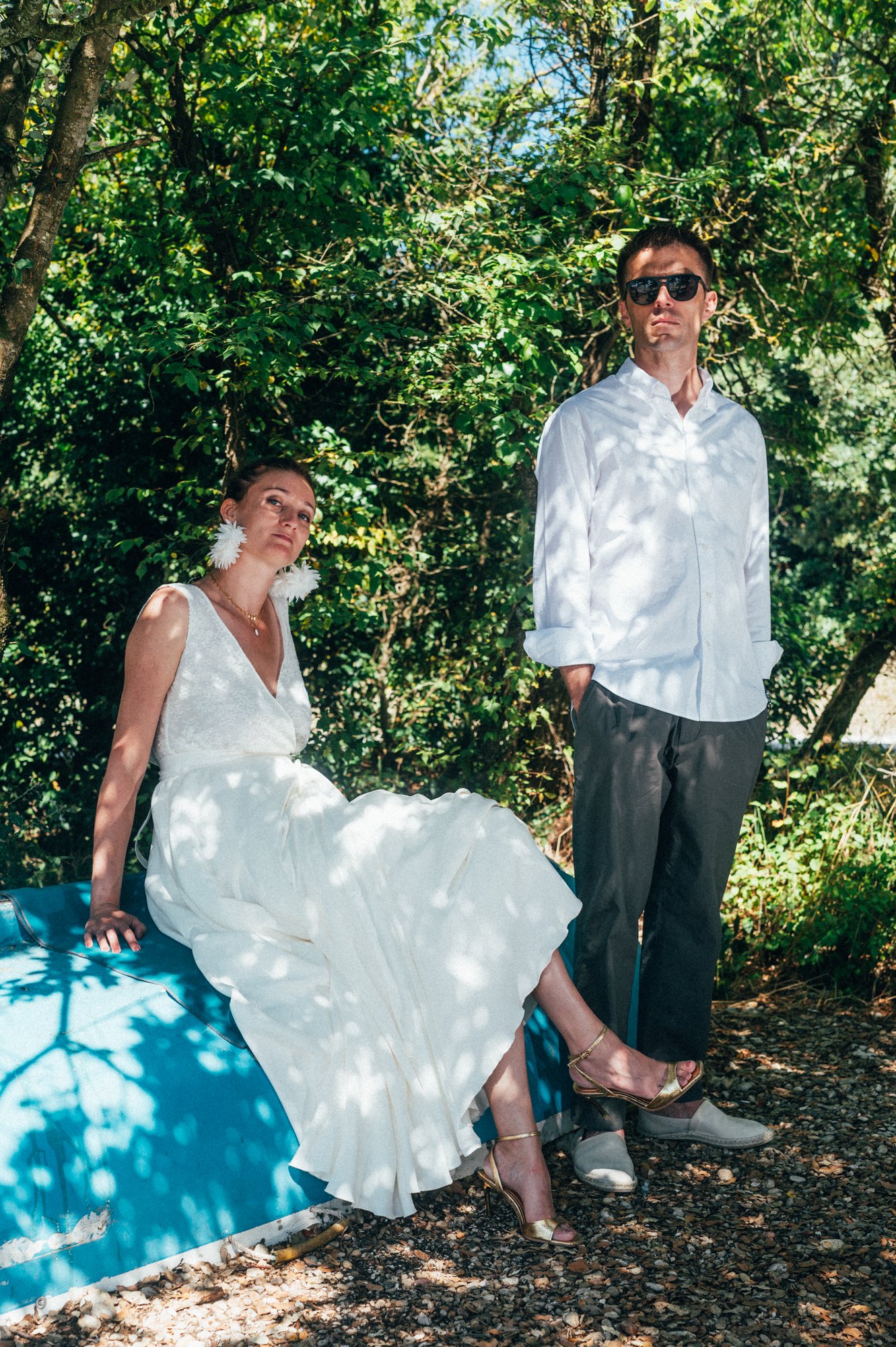 Photo de mariage, Francois est debout les mains dans les poches et Auriane est installée sur la coque d'un bateau retournée