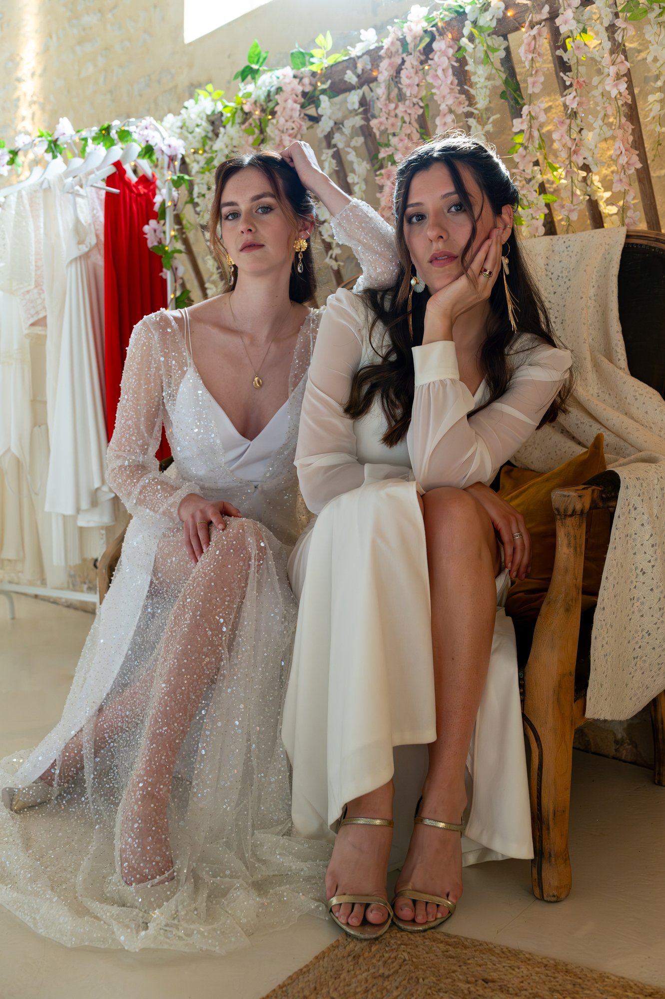 Deux femmes en robe de mariée assisent sur un banc.